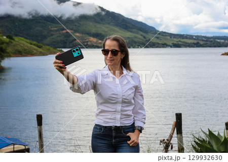 Female tourist taking pictures at the biggest artificial lake in Colombia called Calima Lake located on the mountains of Darien at the region of Valle del Cauca 129932630