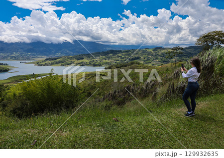 Female tourist taking pictures at the biggest artificial lake in Colombia called Calima Lake located on the mountains of Darien at the region of Valle del Cauca 129932635