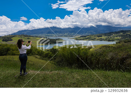 Female tourist taking pictures at the biggest artificial lake in Colombia called Calima Lake located on the mountains of Darien at the region of Valle del Cauca Female tourist taking pictures at the biggest artificial lake in Colombia called Calima Lake located on the mountains of Darien at the region of Valle del Cauca 129932636