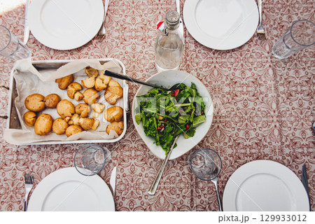 Fresh salad, roasted potatoes and grilled pork belly skewers on table 129933012