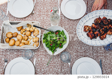 Fresh salad, roasted potatoes and grilled pork belly skewers on table Fresh salad, roasted potatoes and grilled pork belly skewers on table 129933014
