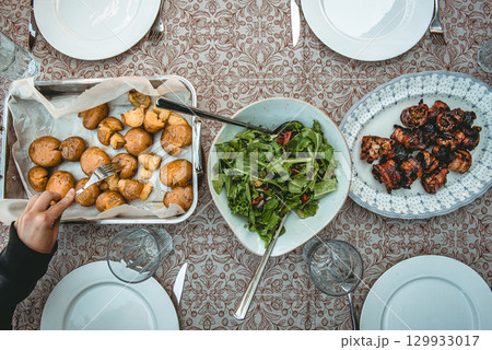 Fresh salad, roasted potatoes and grilled pork belly skewers on table 129933017