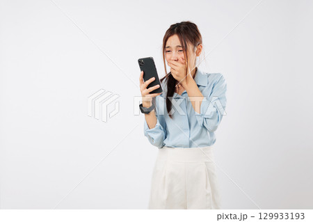 Asian woman shock surprise with phone emotion hold mouth worried after reading mobile news, reacts to shocking content on her phone experiencing disbelief, isolated studio white background Asian woman shock surprise with phone emotion hold mouth worried after reading mobile news, reacts to shocking content on her phone experiencing disbelief, isolated studio white background 129933193
