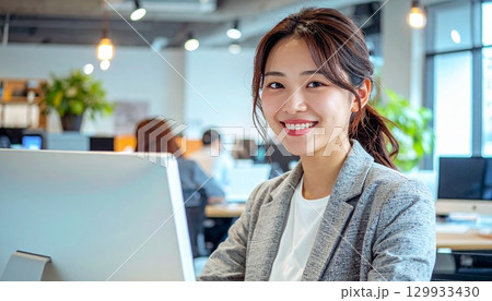 コワーキングオフィスでパソコンを操作する笑顔の日本人女性ポートレート 129933430