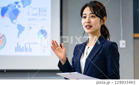 ネイビーブレザーを着た日本人女性が会議室でプレゼンテーションする姿 129933465