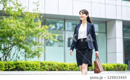 モダンオフィス前を自信満々に歩く日本人ビジネスウーマンの全身ポートレート 129933493