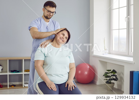 Doctor, chiropractor, osteopath or manual therapist treating neck of happy woman patient 129934132
