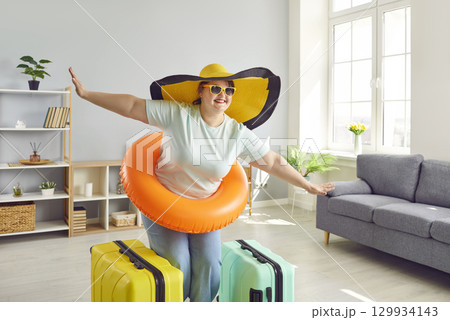 Fat woman in hat and sunglasses getting ready for holiday trip standing with suitcases at home 129934143