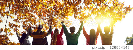 Group of happy friends standing with raised hands at sunset Group of happy friends standing with raised hands at sunset 129934145