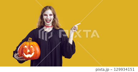 Halloween symbol - big pumpkin in hand of women in carnival costume. 129934151