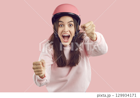Funny woman in pink helmet with excited or scared face expression driving invisible car 129934171