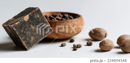 Minimalist Photo of African Black Soap with Shea Nuts on White Background Minimalist Photo of African Black Soap with Shea Nuts on White Background 129934348