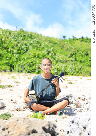沖縄の海岸で三線を奏でる沖縄の少年 沖縄の海岸で三線を奏でる沖縄の少年 129934739