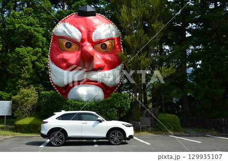大きな天狗面と白い自動車 129935107