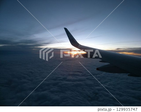 雲海に沈む夕日と飛行機の翼 129935747
