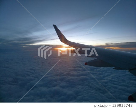 雲海に沈む夕日と飛行機の翼 129935748