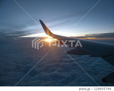 雲海に沈む夕日と飛行機の翼 129935749