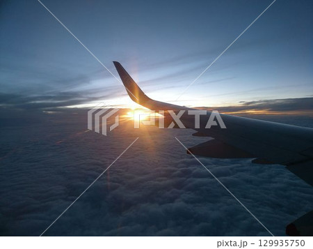 雲海に沈む夕日と飛行機の翼 129935750