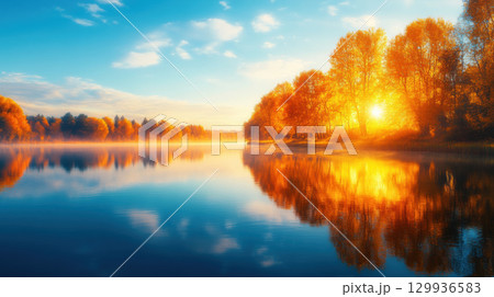 serene lake at dawn with mist rolling over still water, surrounded by vibrant autumn trees reflecting golden sunlight 129936583
