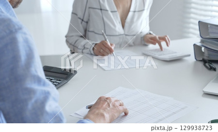 Accounting team working together, reviewing financial reports, using calculator, analyzing data while working at sleek corporate workspace. Audit and taxes concept 129938723
