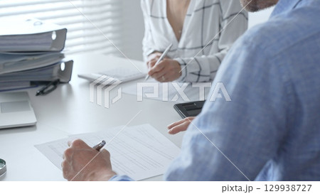 Professional team collaborating, reviewing financial reports, using calculator, analyzing data while working at sleek corporate workspace. Audit and taxes in business Professional team collaborating, reviewing financial reports, using calculator, analyzing data while working at sleek corporate workspace. Audit and taxes in business 129938727