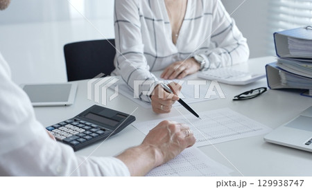 Professional accountants collaborating, reviewing financial reports using calculator, laptop, discussing workplace strategy with team. Audit and taxes concept 129938747