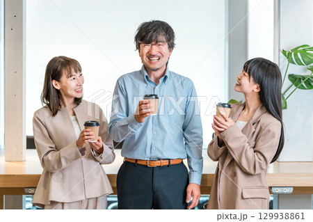 会社,オフィスでコーヒを飲みながら談笑するビジネスマンとビジネスウーマン 会社,オフィスでコーヒを飲みながら談笑するビジネスマンとビジネスウーマン 129938861