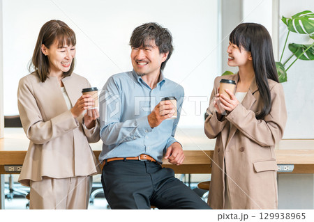 会社,オフィスでコーヒを飲みながら談笑するビジネスマンとビジネスウーマン 129938965
