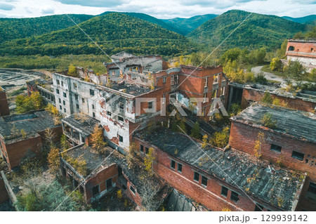 An abandoned mining and processing facility sits in disrepair, with crumbling structures overtaken by nature. 129939142