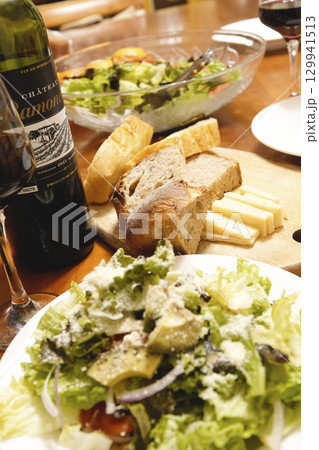 食卓に並べられた前菜のサラダ パンとチーズ ワイン 食卓に並べられた前菜のサラダ パンとチーズ ワイン 129941513