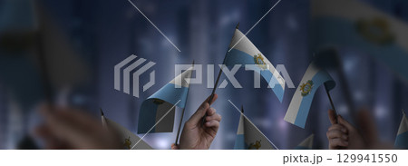 San Marino flags in their hands on a blurred urban background 129941550