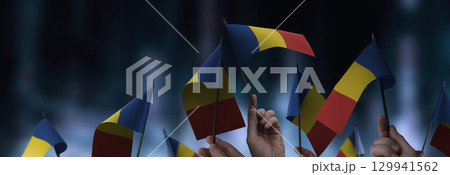 Romania flags in their hands on a blurred urban background 129941562
