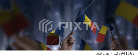 Romania flags in their hands on a blurred urban background 129941565