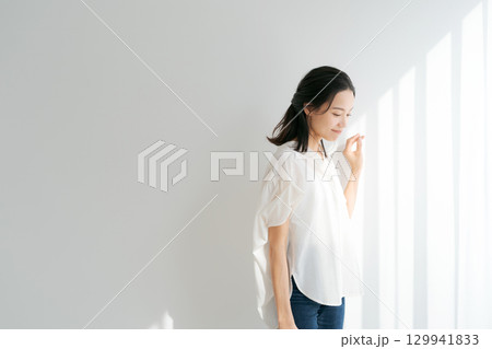 窓辺に日差しを浴びる女性 129941833