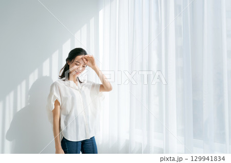 窓辺に日差しを浴びる女性 129941834