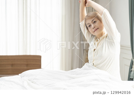 ベッドでストレッチをするシニア女性 129942016