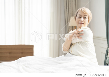 ベッドでストレッチをするシニア女性 129942017