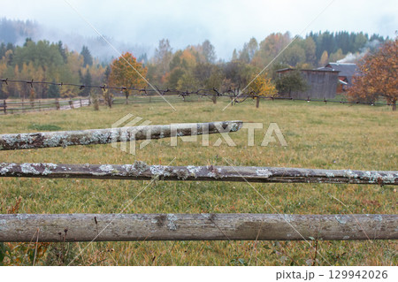 Pasture in autumn mountains. Valley of the Carpathian mountains in morning fog. Meadow  behind wooden fence in forest, Ukraine. Scenic autumn landscape. Rural autumn.Village lifestyle. Scenic woodland 129942026