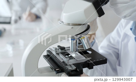 White gloved hands of scientist professional adjusting a microscope in a bright laboratory, emphasizing precision and focus in scientific research. Medicine, healthcare and science concept White gloved hands of scientist professional adjusting a microscope in a bright laboratory, emphasizing precision and focus in scientific research. Medicine, healthcare and science concept 129943007