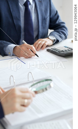 Professional male accountant calculating taxes and analyzing financial data in office setting. Audit and taxes in business 129943064
