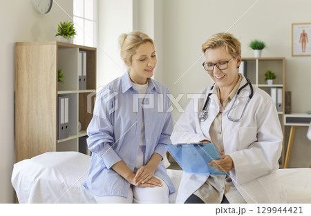 Doctor consulting smiling female patient in clinic Doctor consulting smiling female patient in clinic 129944421