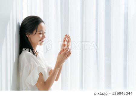 窓際で手をマッサージする女性 窓際で手をマッサージする女性 129945044