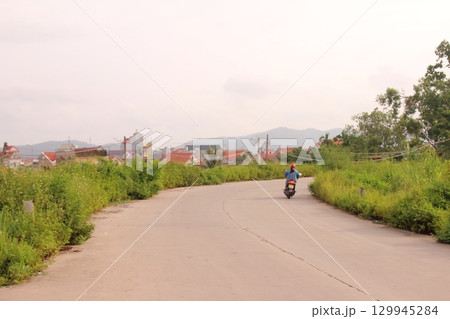 rural road in vietnam with people riding bicycles and motorbikes rural road in vietnam with people riding bicycles and motorbikes 129945284