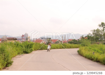 rural road in vietnam with people riding bicycles and motorbikes 129945288