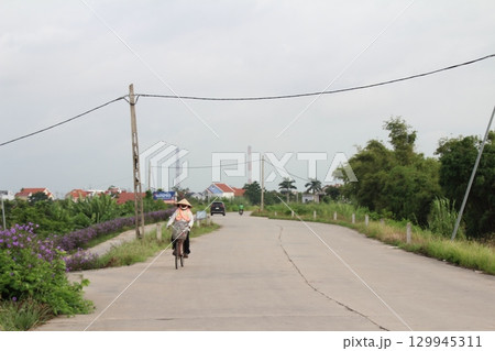 rural road in vietnam with people riding bicycles and motorbikes 129945311