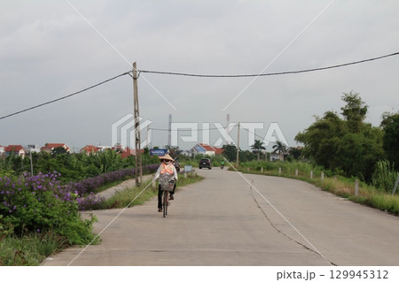 rural road in vietnam with people riding bicycles and motorbikes rural road in vietnam with people riding bicycles and motorbikes 129945312
