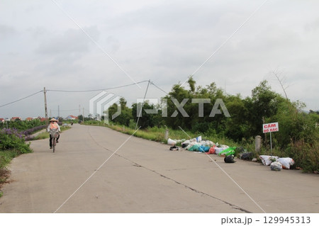 rural road in vietnam with people riding bicycles and motorbikes rural road in vietnam with people riding bicycles and motorbikes 129945313