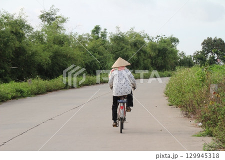 rural road in vietnam with people riding bicycles and motorbikes rural road in vietnam with people riding bicycles and motorbikes 129945318