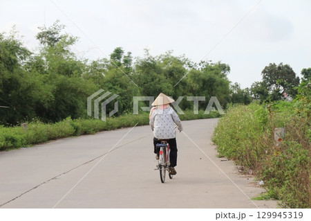 rural road in vietnam with people riding bicycles and motorbikes 129945319