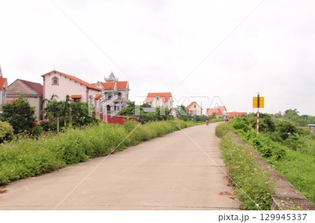 rural road in vietnam with people riding bicycles and motorbikes 129945337